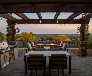 Outdoor patio seating under a pergola with a fire pit and grill